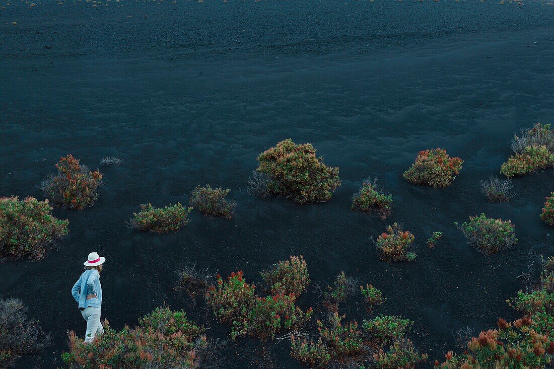 Spanien, Kanarische Inseln, La Palma, Wanderer auf einem Wanderweg in einer wüstenhaften und vulkanischen Umgebung bei Sonnenaufgang