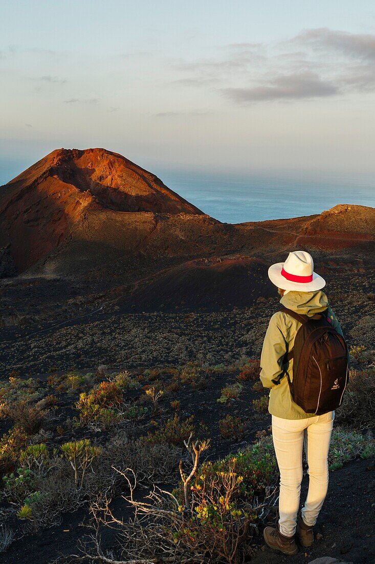 Spain, Canary Islands, La Palma, hiker on a trail in a desert and volcanic environment at sunrise