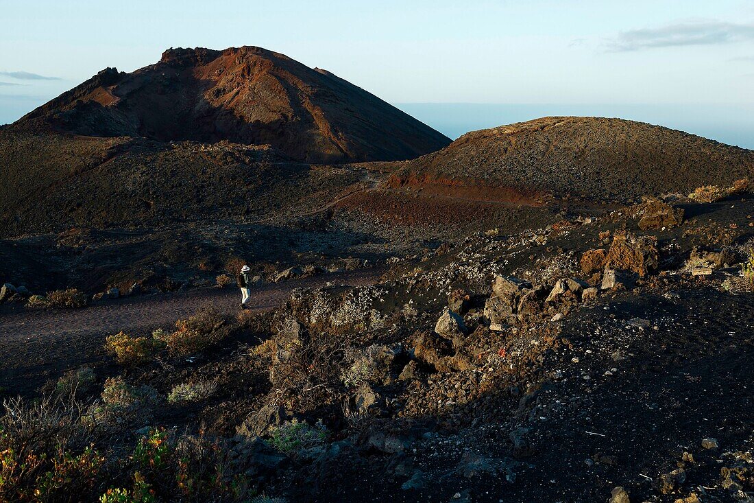 Spain, Canary Islands, La Palma, hiker on a trail in a desert and volcanic environment at sunrise