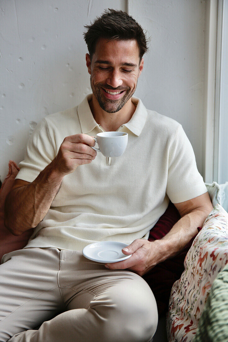 Mann in cremefarbenem Poloshirt genießt Espresso