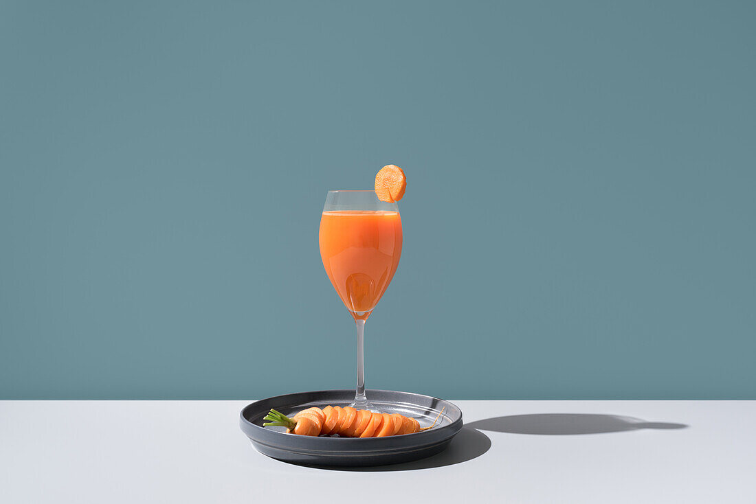 Ein exquisites Arrangement mit einem erfrischenden Cocktail, garniert mit einer Scheibe Zitrusfrucht und geräuchertem Lachs, zart platziert auf einem eleganten schwarzen Teller, der weiche Schatten auf eine minimalistische Oberfläche wirft.