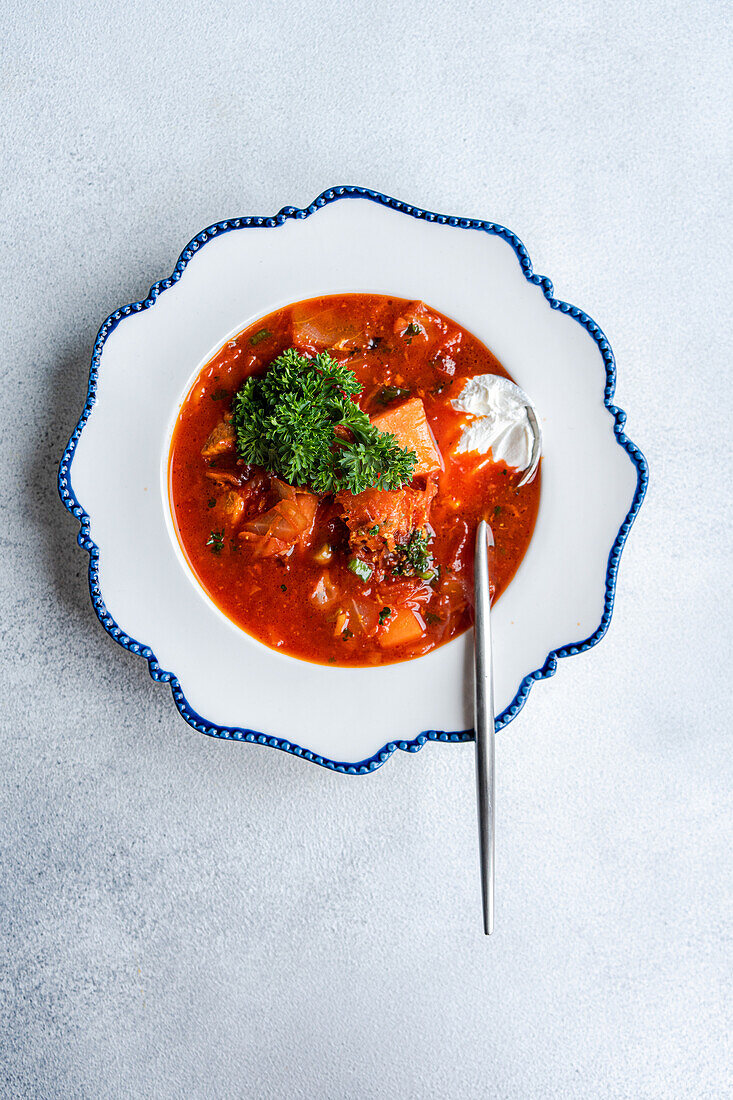 Pikante ukrainische Borschtschsuppe mit Roter Bete und zartem Fleisch, serviert mit einem Klecks saurer Sahne, garniert mit Petersilie