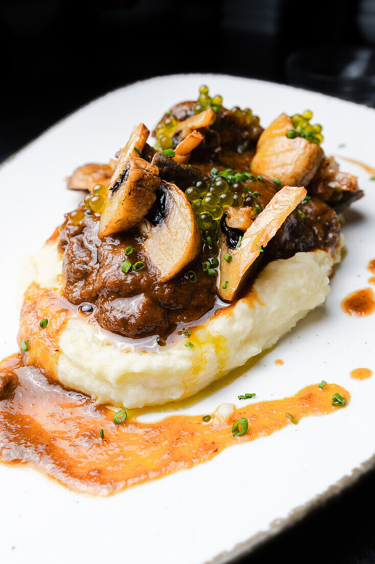 Succulent pork cheeks cooked in Pedro Ximene reduction, served over creamy mashed potatoes, garnished with mushrooms and chives.