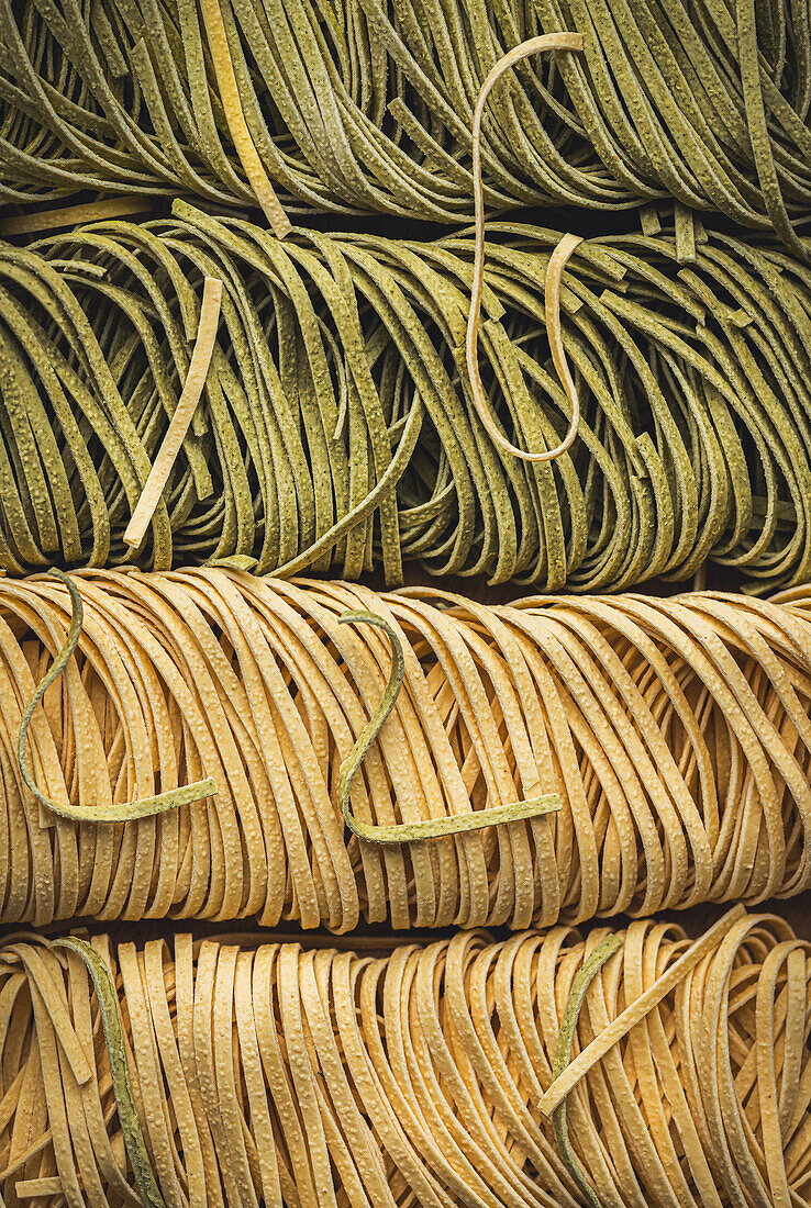 Close-up of homemade herb-infused Italian pasta, neatly aligned and showcasing fresh ingredients.