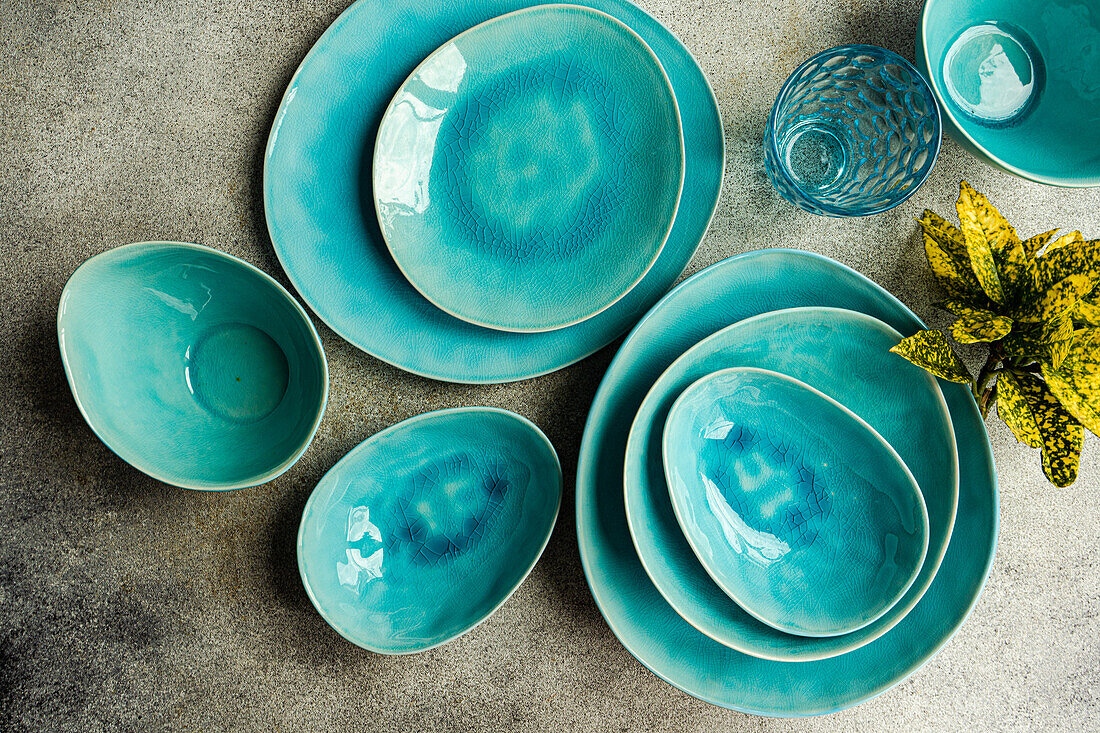 Top view of a stylish table setting featuring bright turquoise ceramic dinner plates, bowls, and glassware. Ideal for modern dining presentations.