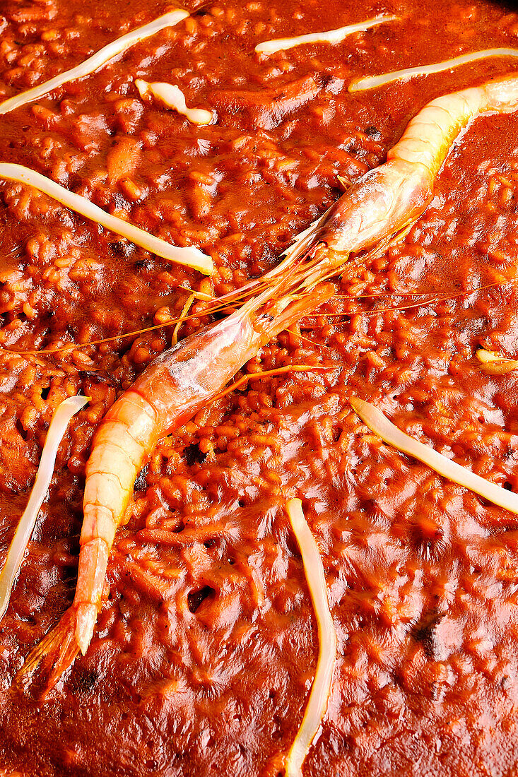 A close-up image showcasing a savory traditional seafood paella with a succulent whole prawn prominently displayed.