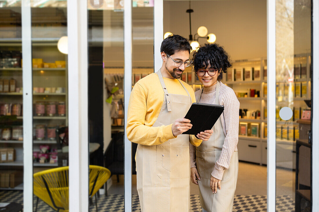 Two small business owners with digital tablet at entrance of a boutique store