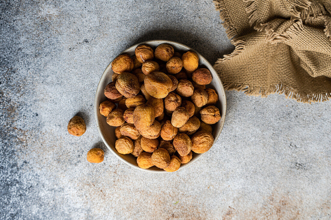 Bowl of Arashan Kandak, sun-dried sweet wild apricots from Central Asia, displayed on a rustic background, representing a healthy snack