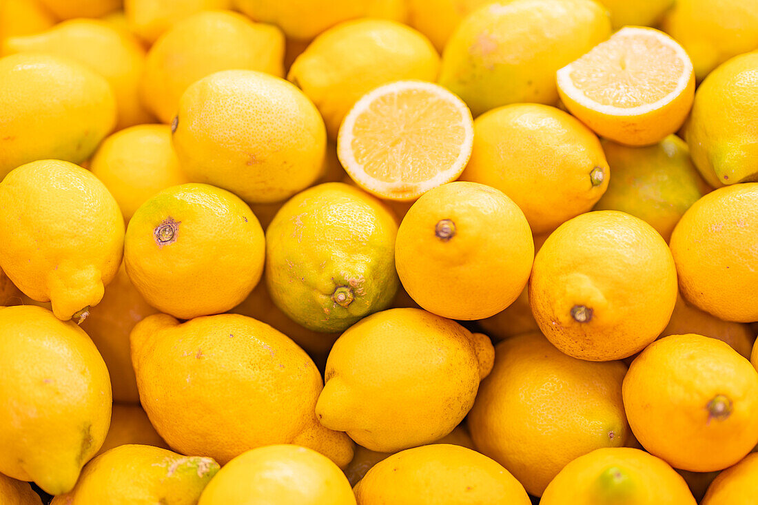 A vibrant, close-up image of fresh, ripe lemons with one cut lemon slice revealing juicy interior