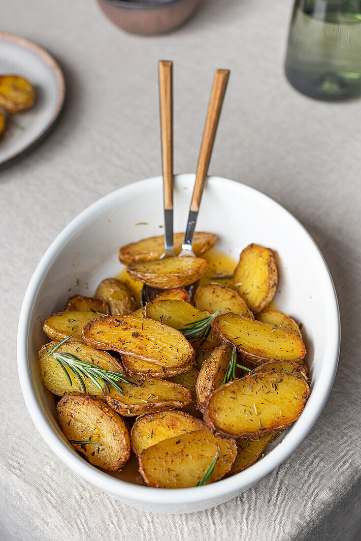 From above bowl of golden roasted potatoes seasoned with herbs, captured from an angled view, ready to be enjoyed.