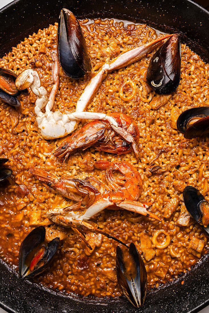 Top vie of traditional seafood paella, rich in squid, mussels, and shrimp, simmered to perfection in a savory fish broth and highlighted by the crispy socarrat.