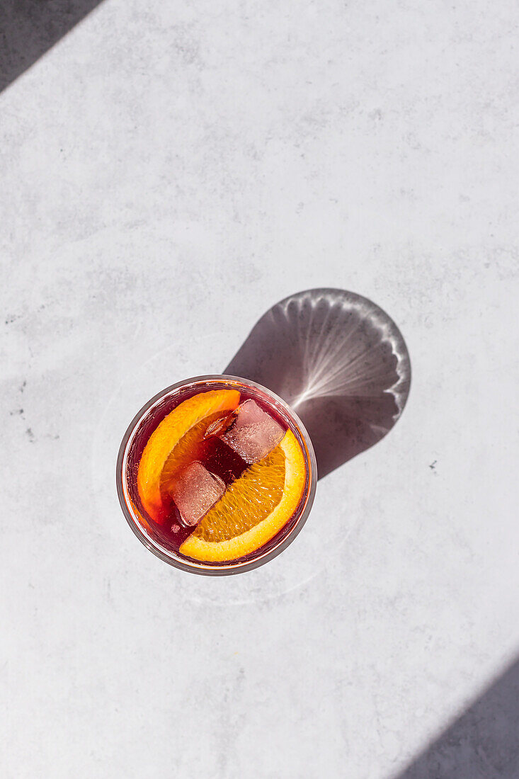 Overhead shot of a cold Tinto de Verano, a classic Spanish cocktail, with ice and orange slice served on a bright surface