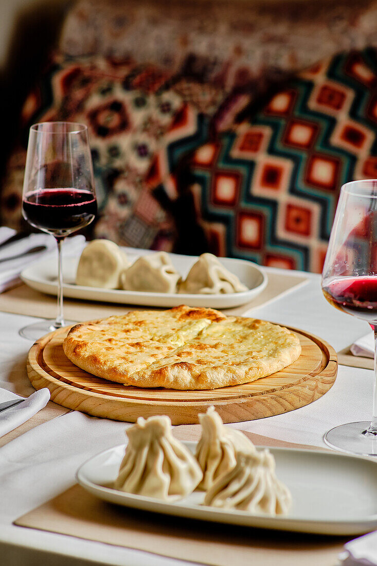 A tempting selection of Georgian cuisine featuring Khachapuri, Khinkali, and wine served on a wooden board and traditional plates