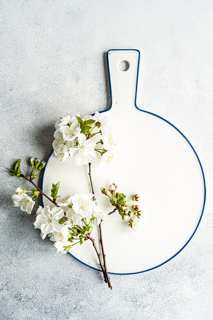 A pristine white ceramic cutting board adorned with delicate cherry blossoms offers a fresh, springtime vibe