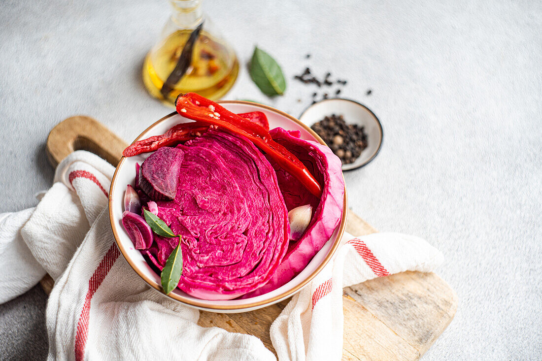 A bowl of colorful fermented cabbage mixed with beetroot, adorned with spicy red peppers and cloves of garlic, evoking a healthy, flavorful vegetarian dish.