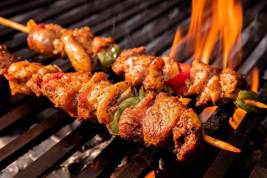 Saftige mexikanische Grillspieße mit Hähnchen, Paprika und Zwiebeln, die über glühender Holzkohle gegrillt werden und eine köstliche Verkohlung und leuchtende Farben aufweisen.