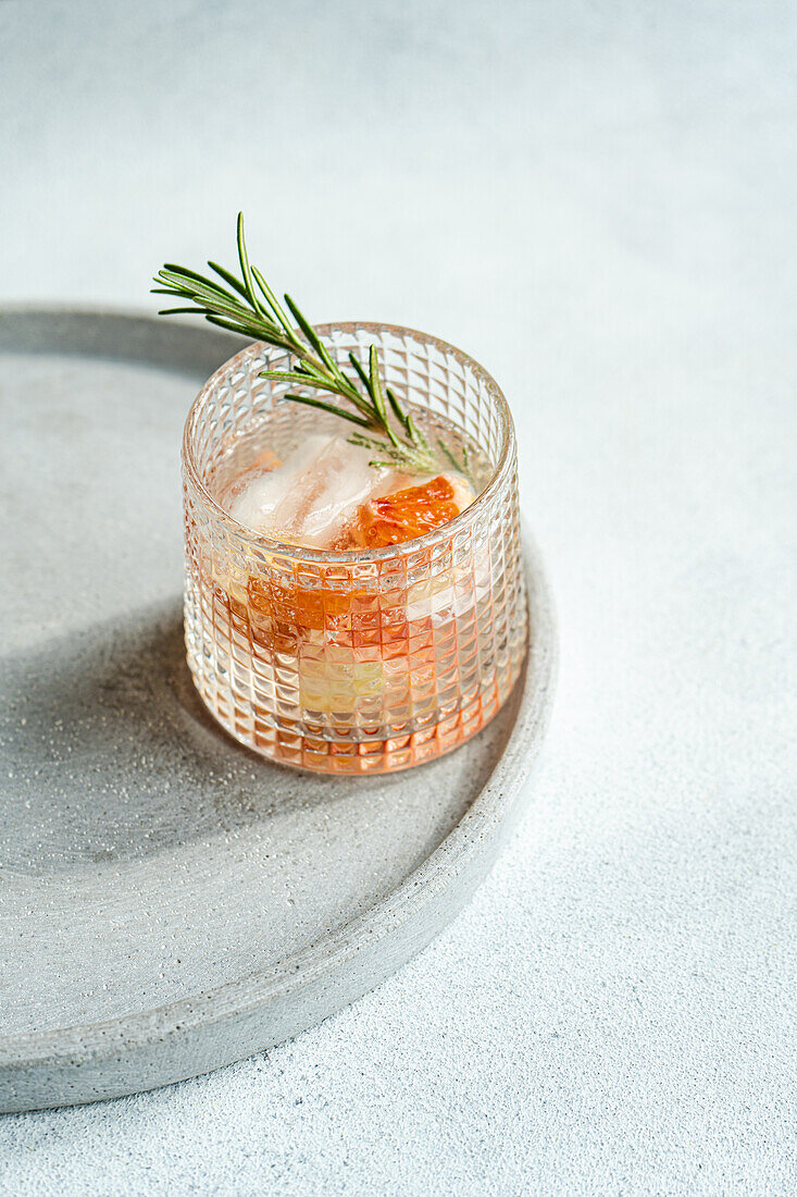 Ein handwerklich hergestellter Wodka-Tonic-Cocktail mit Grapefruit und Rosmarin, der auf einem strukturierten Tablett für ein gehobenes Serviererlebnis ruht