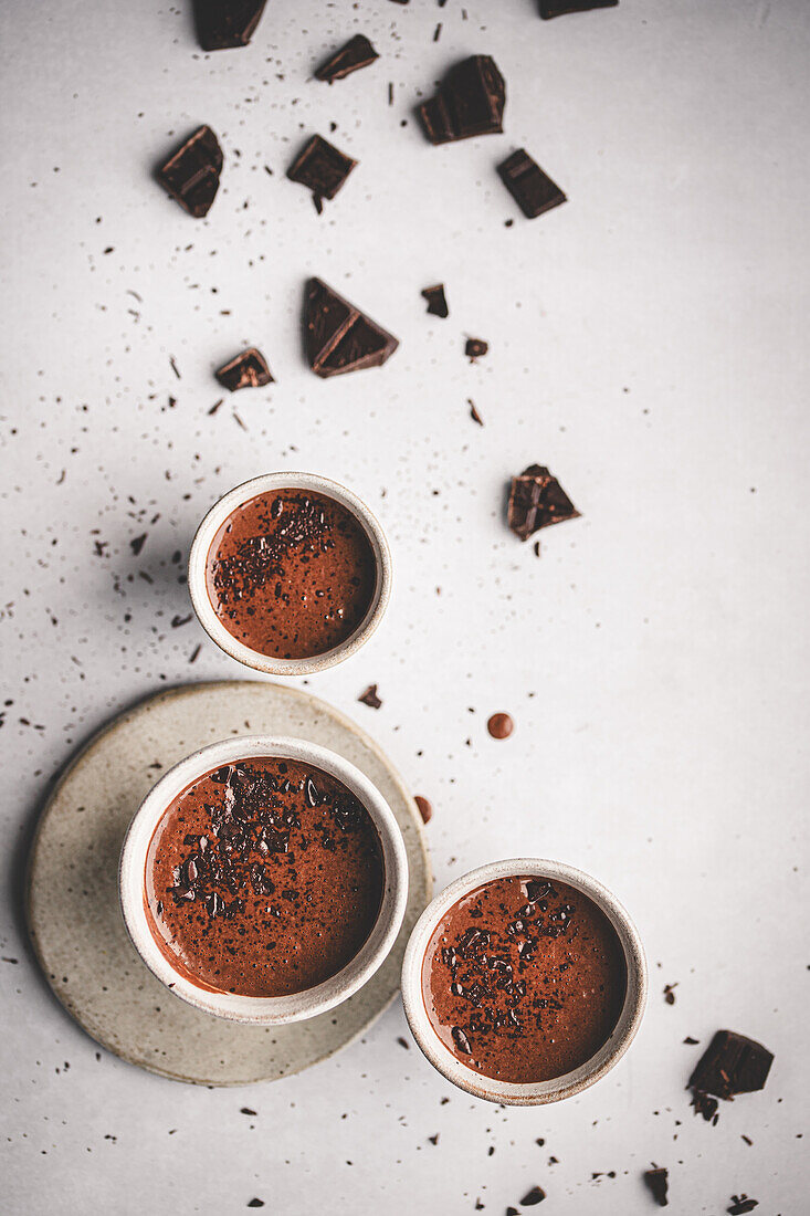 Top-down view of three chocolate lava cakes sprinkled with chocolate shards, elegantly presented on a white surface