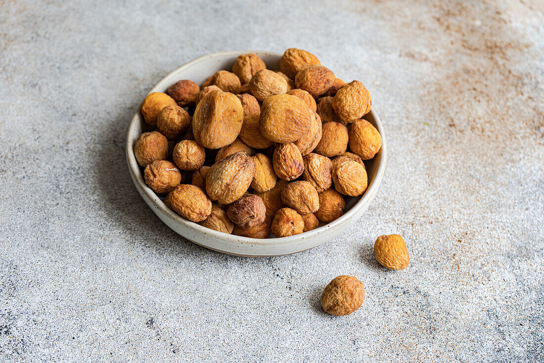 Bowl of Arashan Kandak, sun-dried Central Asian sweet wild apricots, on textured background