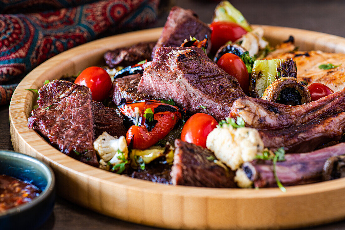 A succulent arrangement of grilled steak and a variety of fresh, colorful vegetables served on a rustic wooden platter, perfect for a hearty meal