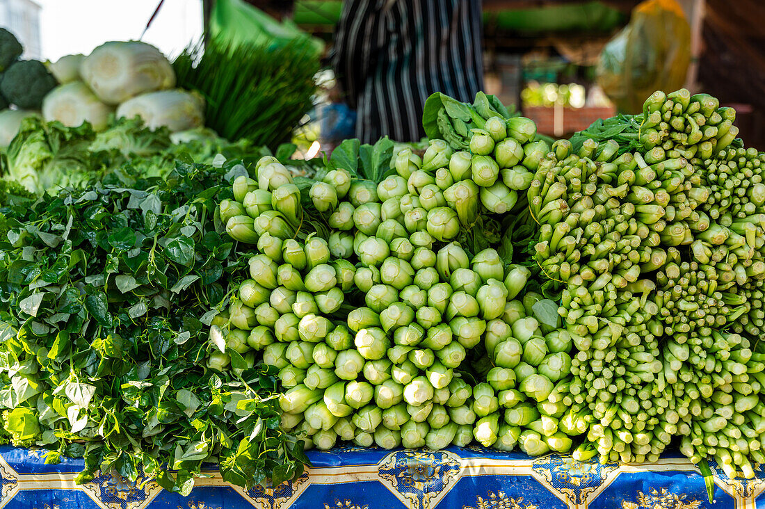 Leuchtend grüne Brunnenkressebündel, die auf einem lokalen Markt in Hanoi frisch arrangiert sind und das üppige Gemüse zum Verkauf anbieten.