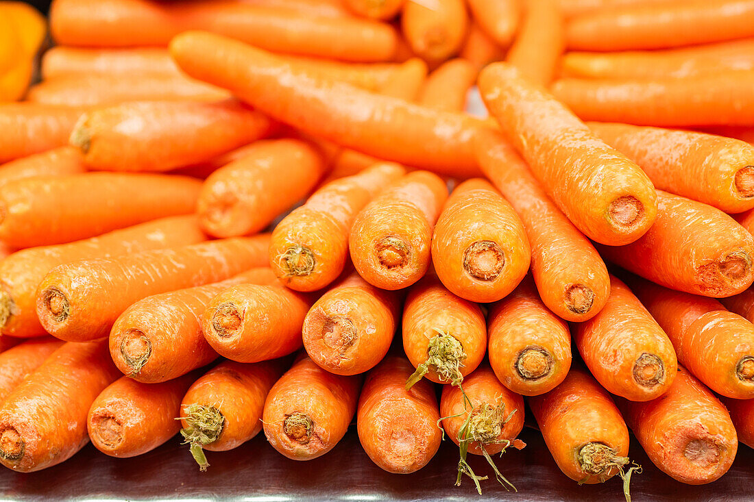 An abundance of vibrant, fresh carrots piled up for sale at a local grocery market