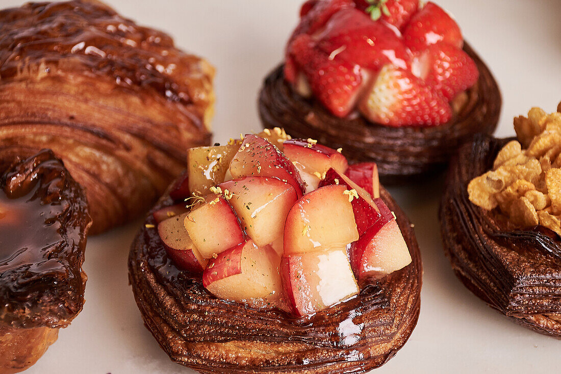 Close-up of decadent pastries topped with glaze and fresh fruit, showcasing culinary artistry and attention to detail.