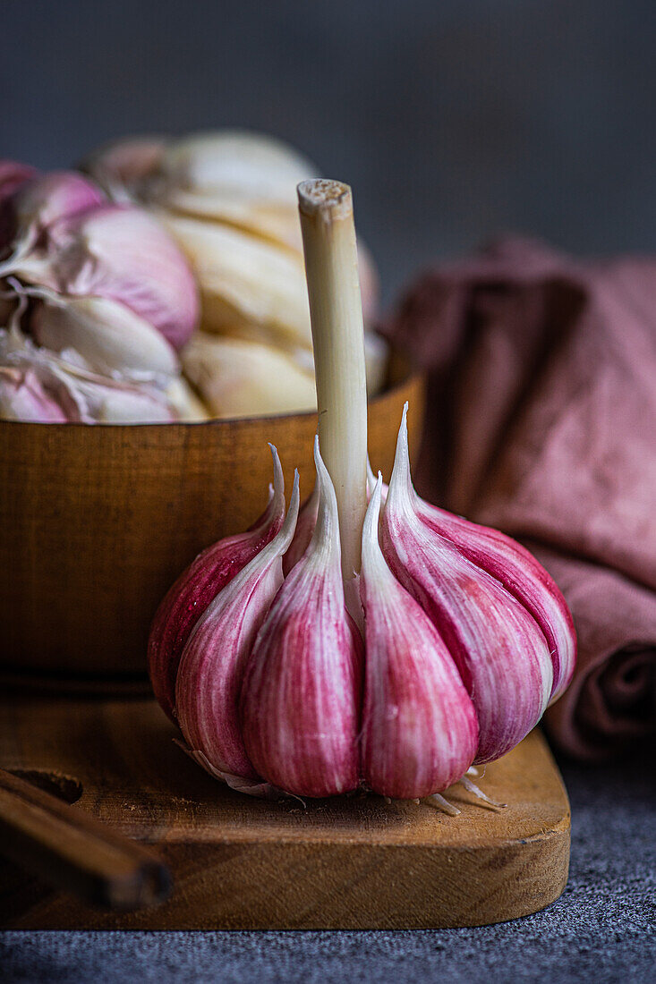 A close-up view of vibrant pink garlic cloves, artistically presenting their fresh, organic nature on a rustic wooden board, enhanced by a softly blurred backdrop and warm tones