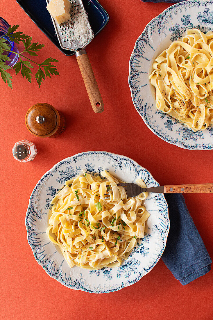 Eine Nahaufnahme von Fettuccine Alfredo, serviert auf einem rustikalen Tisch mit Parmesankäse