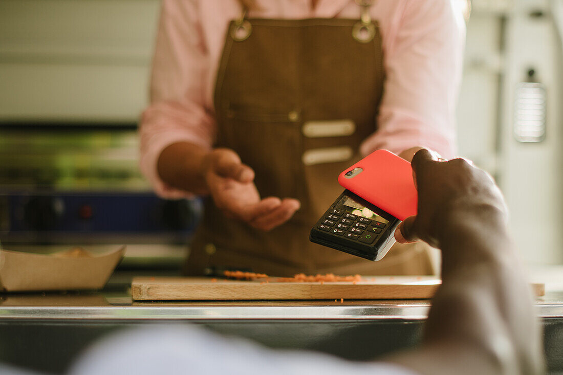 Soft focus of anonymous African American male using smartphone to pay for order to cook working in food truck