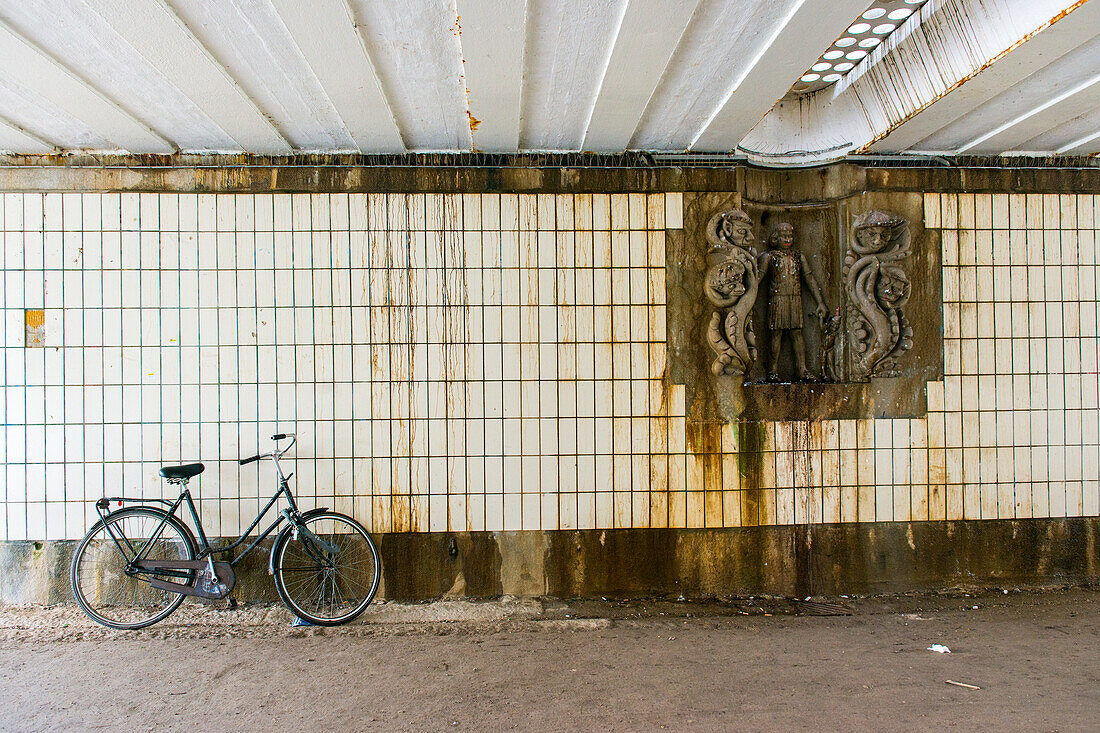 Amsterdam, Netherlands. Underneith a Vondelpark bridge an artwork and a parked bike.