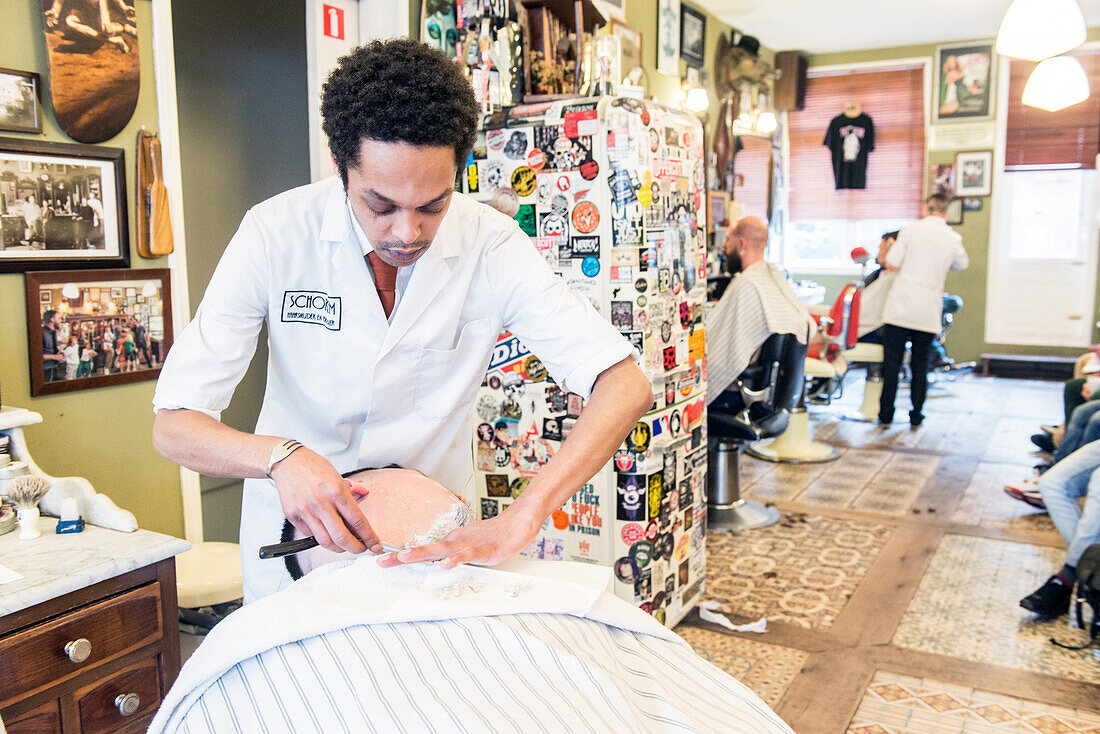 Professional Barber & Haircutter Shaving his Customer inside Schorem Barber Shop at Nieuwe Binnenweg, Rotterdam, Netherlands.