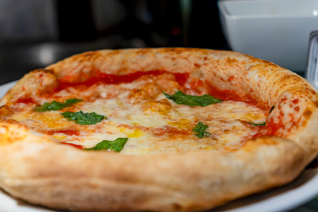 Eine Nahaufnahme einer frisch gebackenen neapolitanischen Pizza mit kräftiger Tomatensauce, geschmolzenem Mozzarella-Käse und frischen Basilikumblättern auf einer knusprigen Kruste