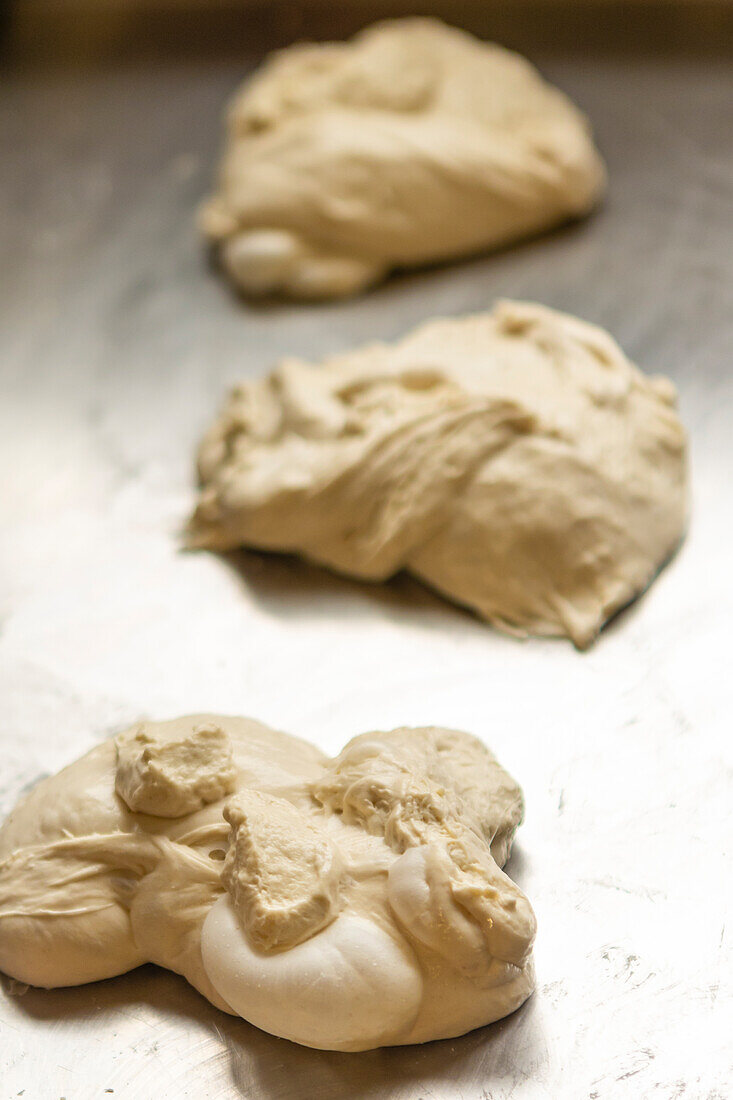 Close-up image of freshly made pizza dough resting on a floured kitchen surface, capturing the initial stage of pizza preparation