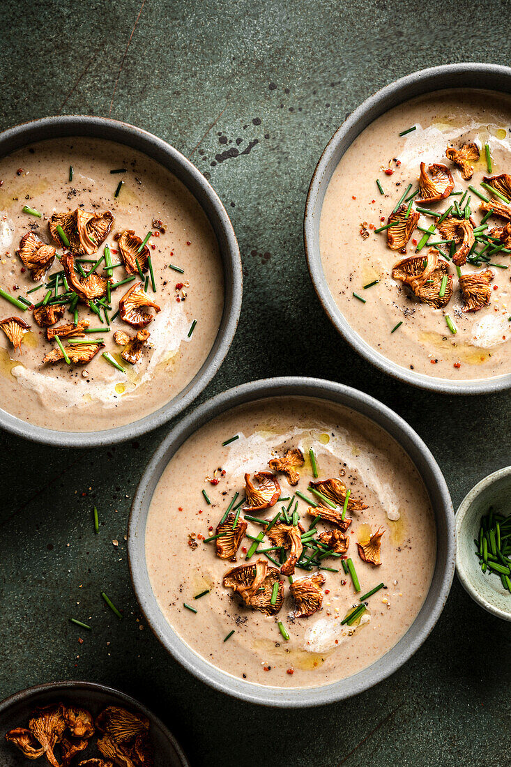 Mushroom soup bowls with wild mushrooms on a green surface