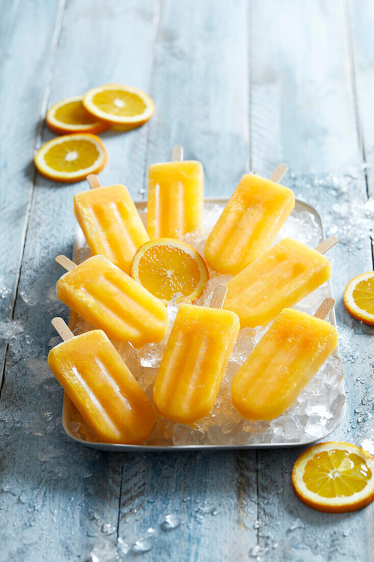 Homemade ice-cold orange popsicles on crushed ice