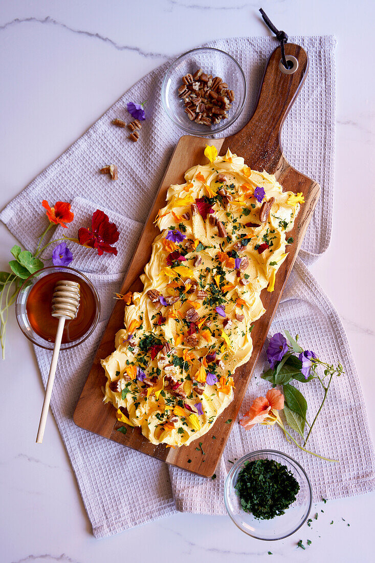 Butter board with herbs, pecans and edible flowers.