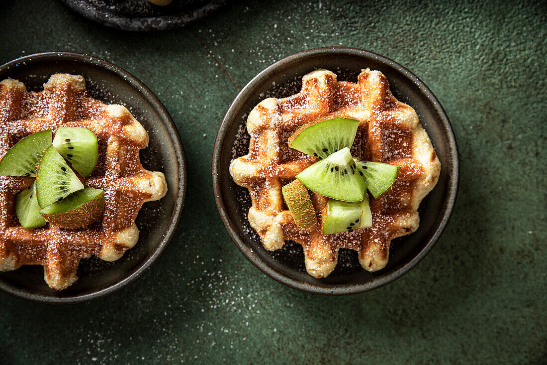 Morgenwaffeln mit Kiwi und Gabel auf einer grünen Fläche