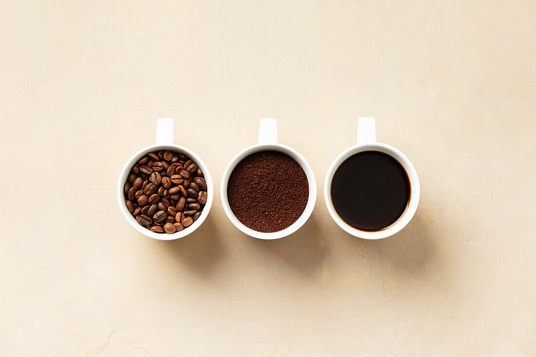 Sequential representation of coffee beans, coffee grounds and brewed coffee in white cups.