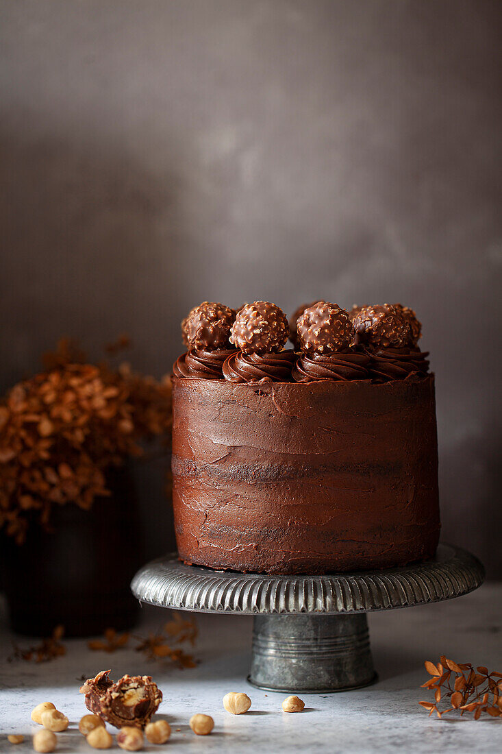 A chocolate layer cake covereed in chocolate ganache and hazelnut chocolates