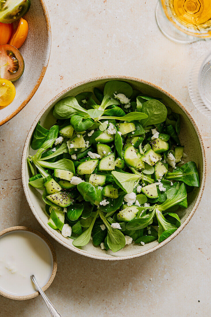 Cucumber and lamb's lettuce salad with feta and yoghurt dressing on a stone background