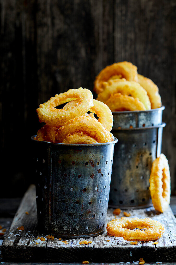 Homemade crispy fried onion rings in a metal cup