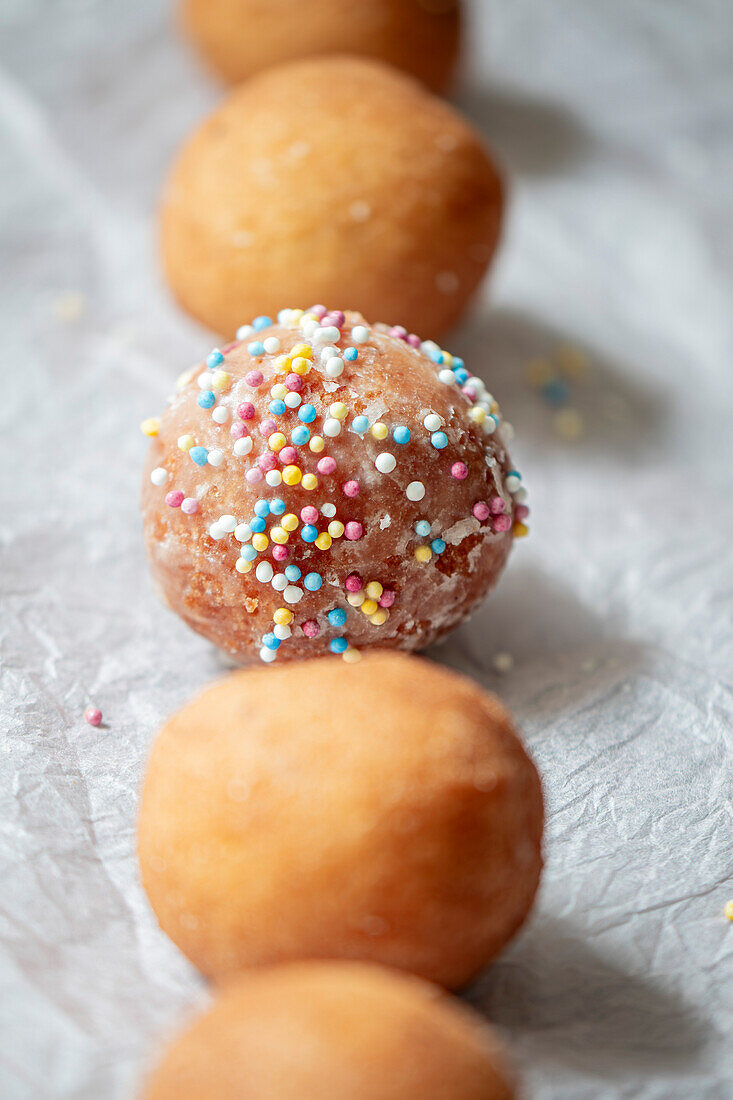 Row of doughnut holes. One was sprinkled with hundreds and thousands.