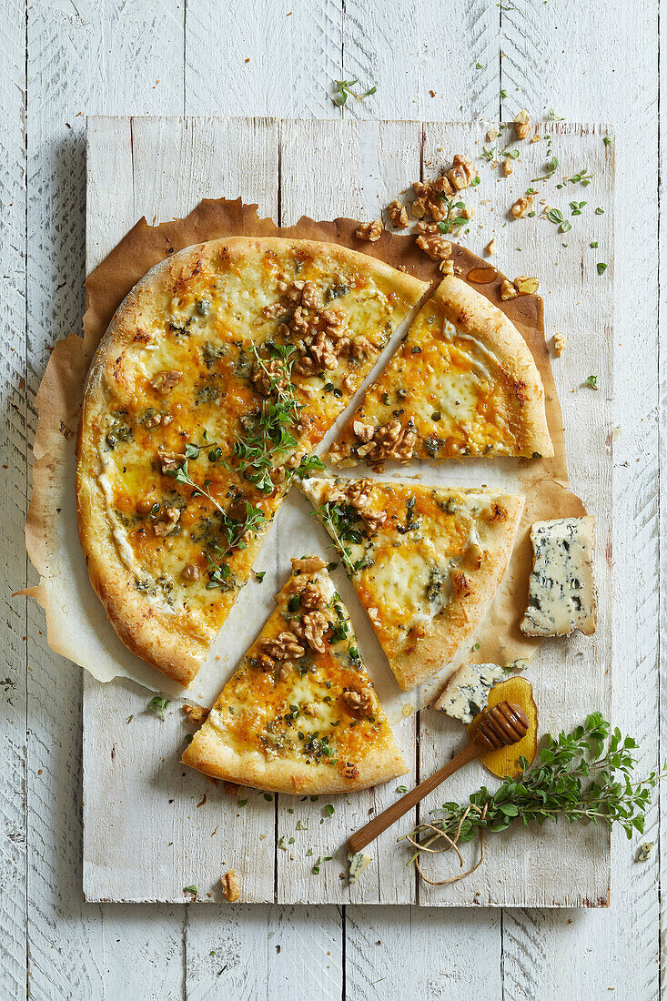 Vier-Käse-Pizza mit Blauschimmelkäse, Walnüssen, Honig und Oregano auf einem weißen Holzhintergrund