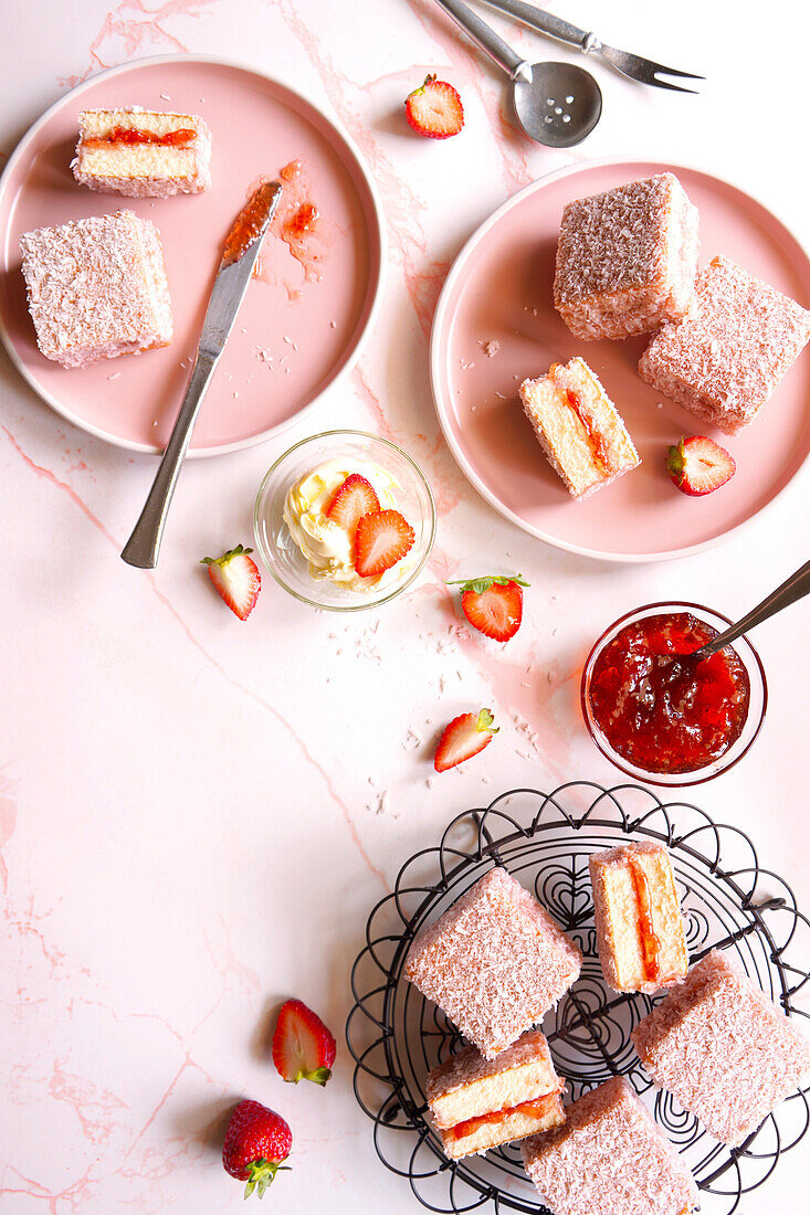 Australian pink lamington Small square cake with strawberry jam and coconut covering.