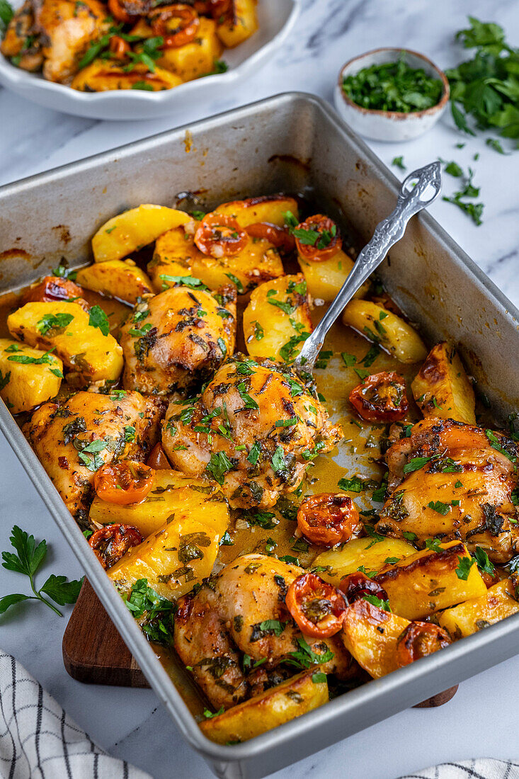 Baked chicken thighs and potatoes in a baking dish, photographed from the front.