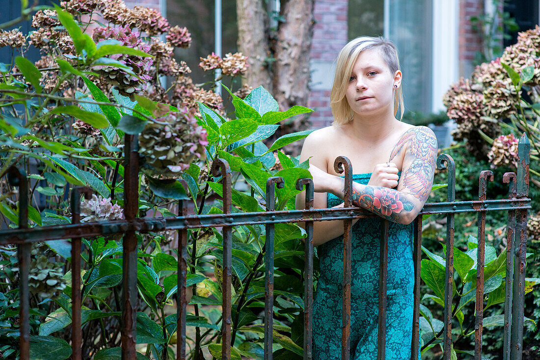 Portrait Young Woman with Tatoos in Residential Garden. Tilburg, Netherlands.