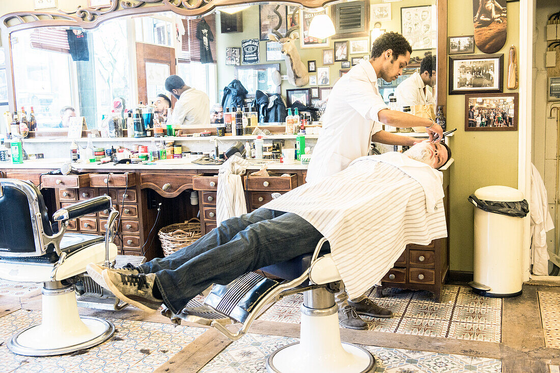 Professional Barber & Haircutter Shaving his Customer inside Schorem Barber Shop at Nieuwe Binnenweg, Rotterdam, Netherlands.