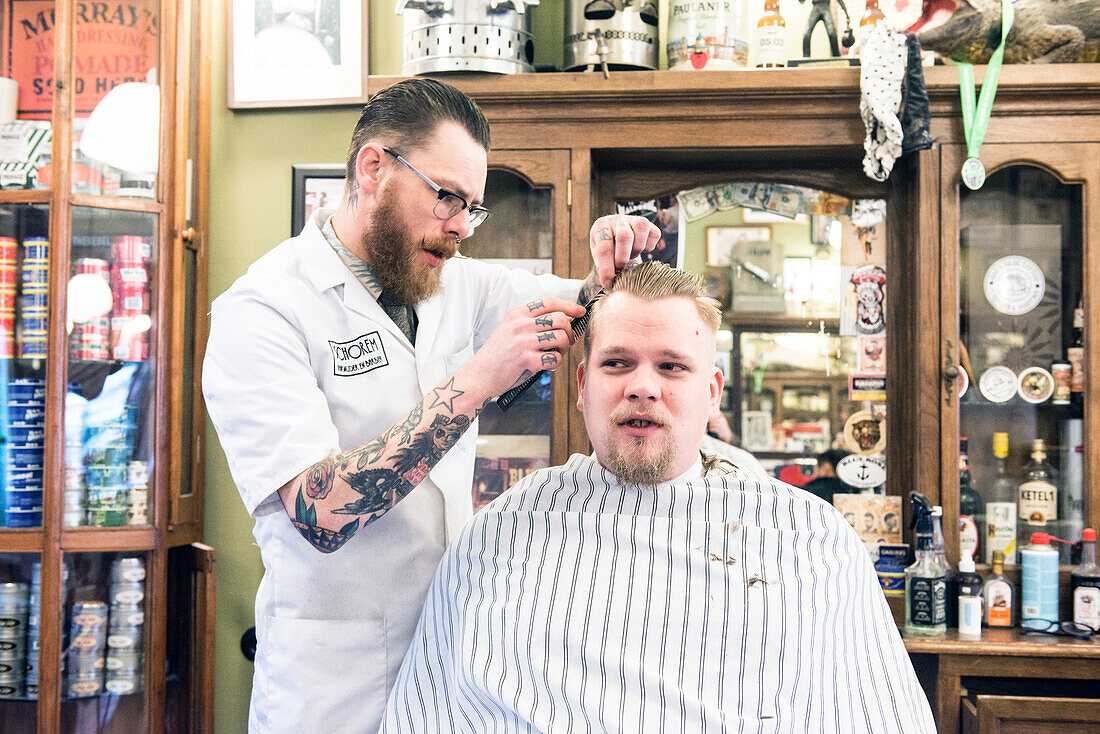 Professioneel barbier verzorgt het haar van een van zijn mannelijke klanten in de barbershop.