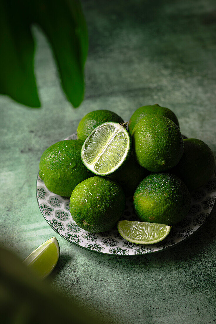 Limetten auf einem Teller und grünem Hintergrund